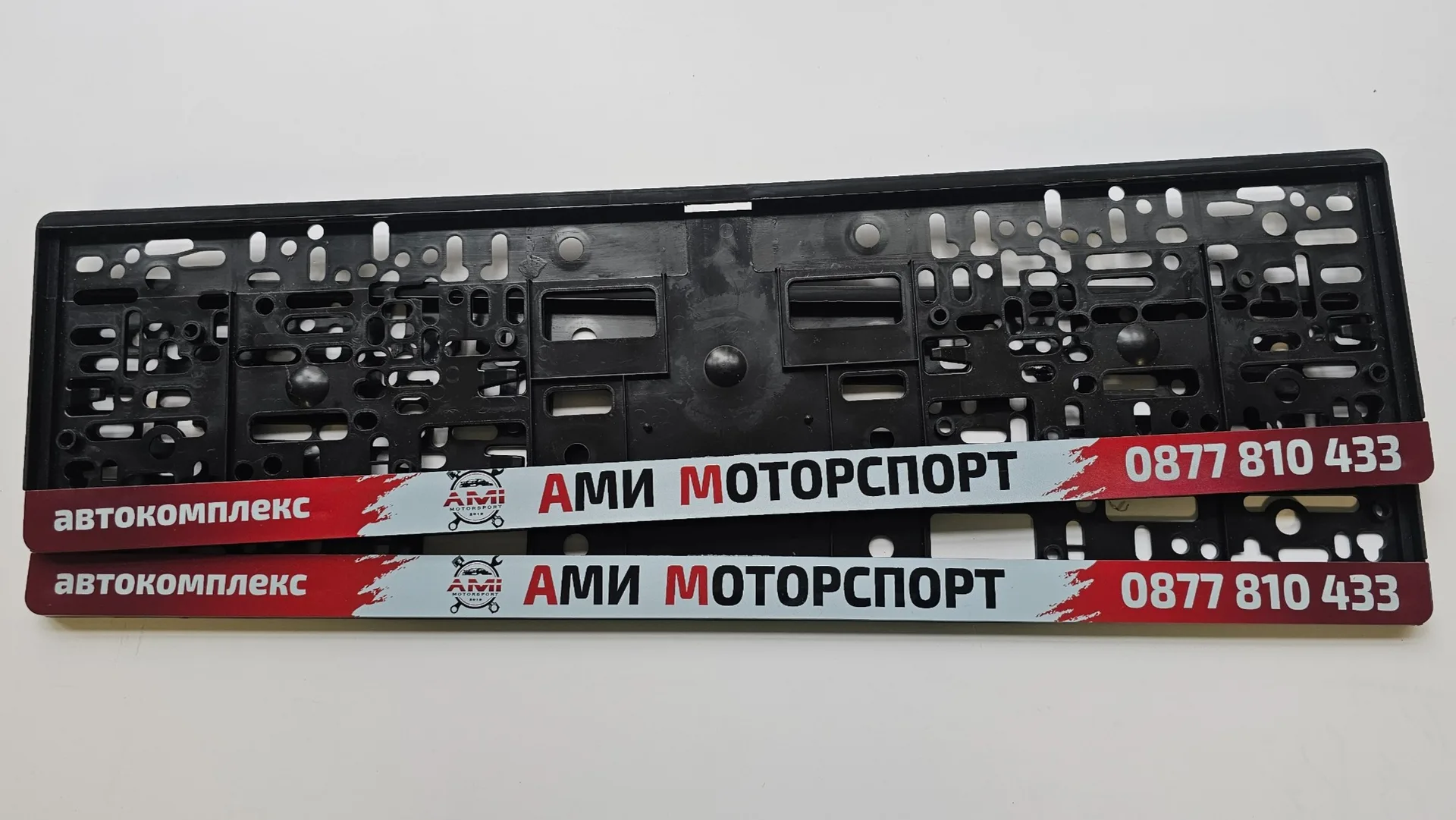 Фирмени рекламни рамки за регистрационни номера AMI Motorsports с UV печат по индивидуален дизайн от nameyourcar.store — персонализирана рамка за регистрационен номер с UV печат от NameYourCar.store