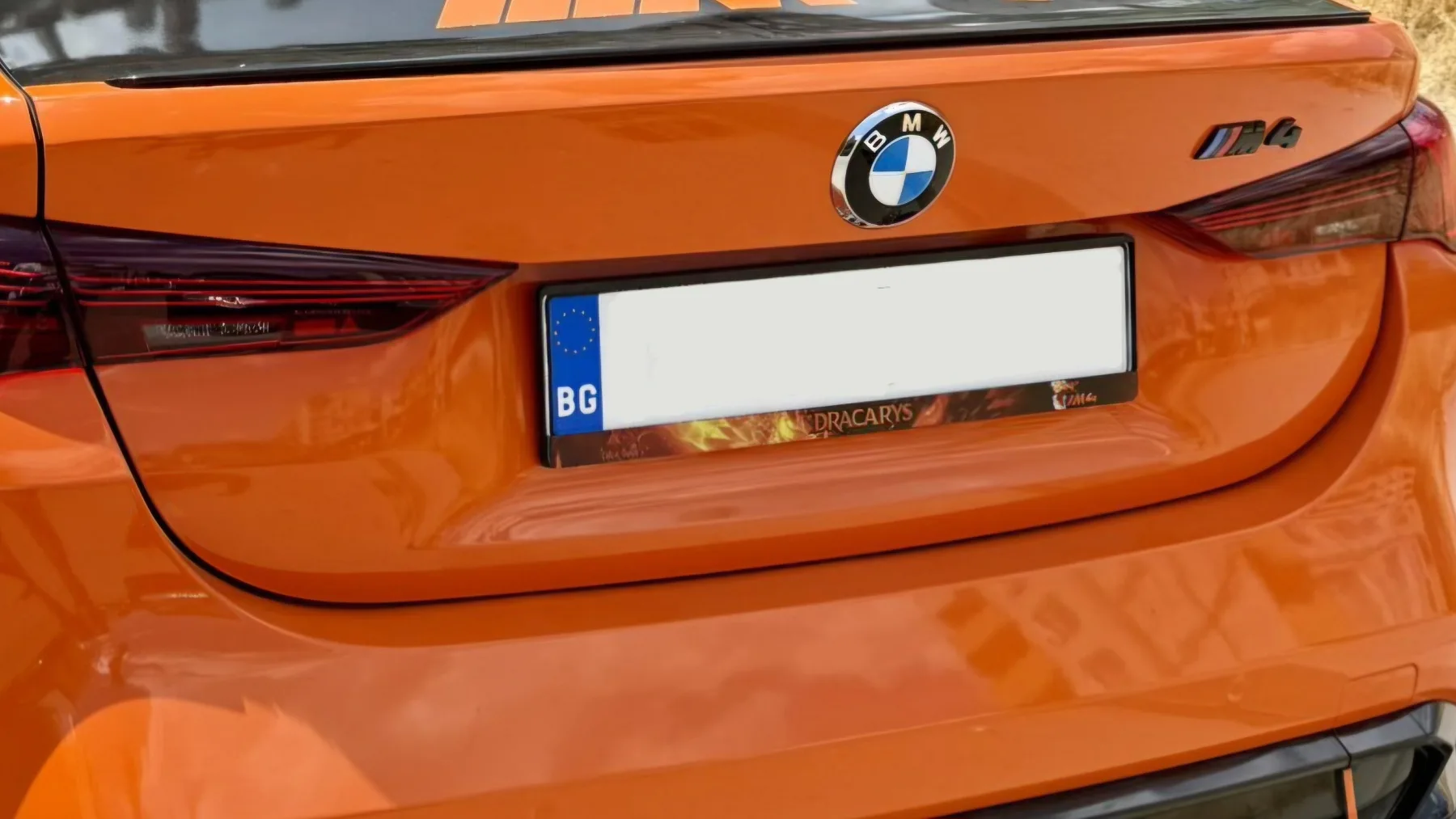 personalized DRACARYS license plate frame on an orange BMW M4 — license plate frame for BMW